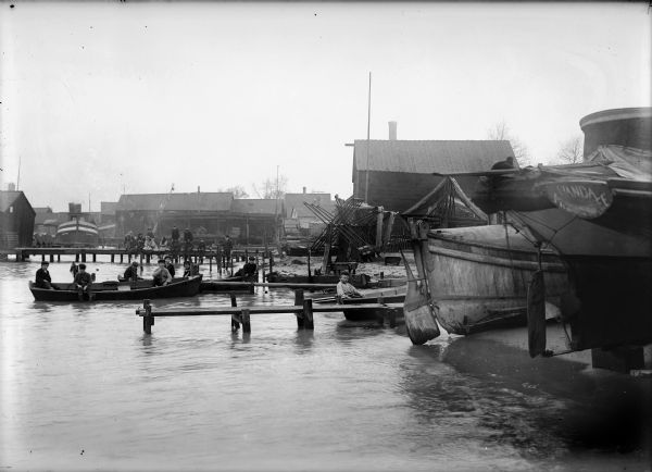 Children gathered on fishing boats and piers in a harbor.