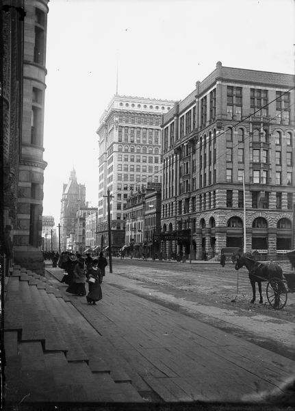 East Wisconsin Avenue showing men and women on the sidewalks and the Hotel Pfister in the background.