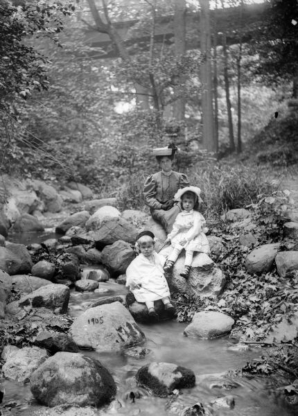 Alma Reinhardt Taylor posed on rocks near a stream with her daughters Ellen Taylor Higgins and Donna Taylor Adams (front).