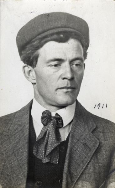 A portrait of J. Robert Taylor wearing a hat.