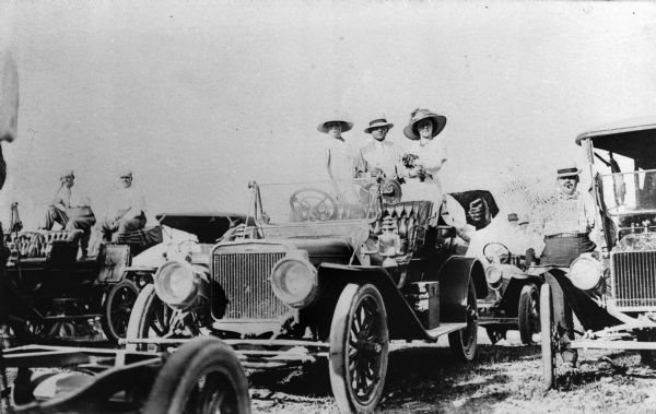 Men and women are lined up in their parked cars to watch the State Fair automobile race.