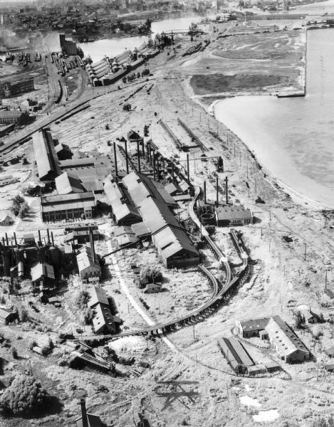 Aerial view of a steel mill near an adjacent unidentified body of water.