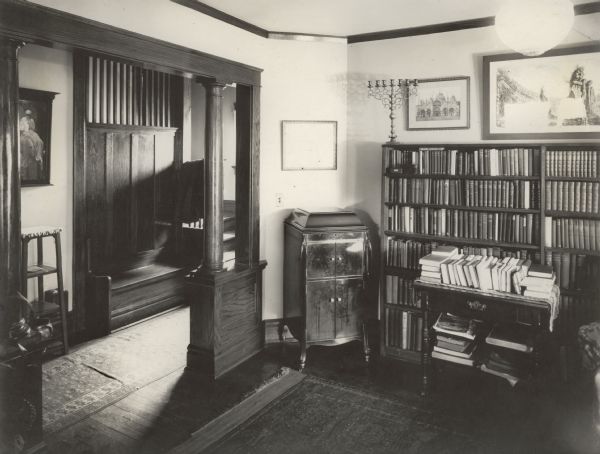 A view from the library into the entryway of the Richard Lloyd Jones residence, 1010 Walker Court (now 1010 Rutledge  Court).  He was editor and publisher of the Wisconsin State Journal.  It shows a built-in bench beside the stairway.  Framed prints of Venice and of classical ruins hang above the bookcase.  A Victrola-style phonograph stands in the corner.  The menorah on the bookcase was purchased by Georgia Lloyd Jones in New York.