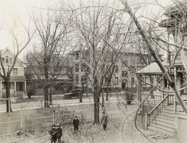 Children in the backyard of the Walker mansion.  Buildings along the west side of the 600 block of South Brearly Street including Monona Apartments can be seen.  A corner of the William Walker Mansion, 1007 Spaight at Brearly, is on the right.