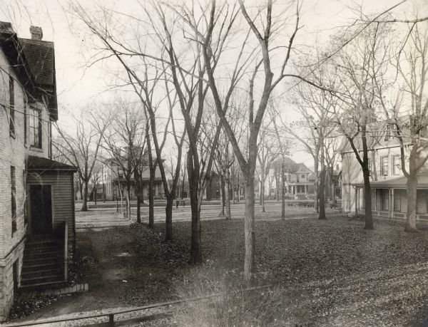 1000 Block of Spaight Street, Marquette neighborhood. In the background, houses line the north side of Spaight Street, 1008 Spaight (the Snell House) and 1030 Spaight. In the foreground, the William Walker Mansion, 1007 Spaight Street is on the left, the Gill house, 1021 Spaight Street is on the right. Two boys are walking in the background, one slightly blurred from movement.