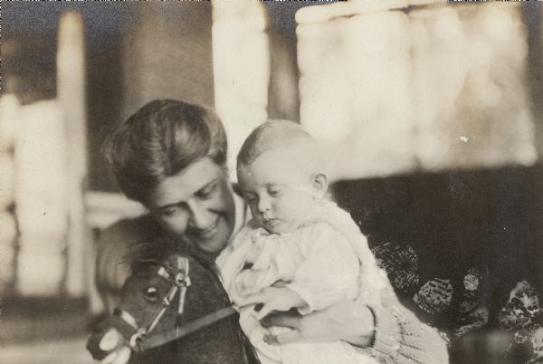 Georgia Lloyd Jones, wife of Richard Lloyd Jones, holds her son on a rocking horse.
