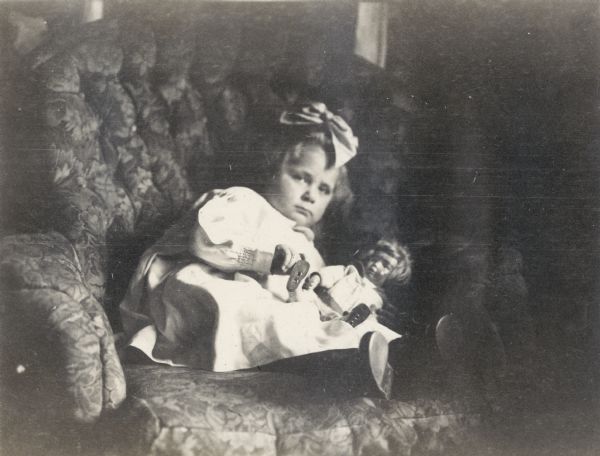Florence Lloyd Jones, known as Bis or Bisser, born Oct. 9, 1913, daughter of Richard & Georgia Lloyd Jones, sitting with her doll in an upholstered chair.
