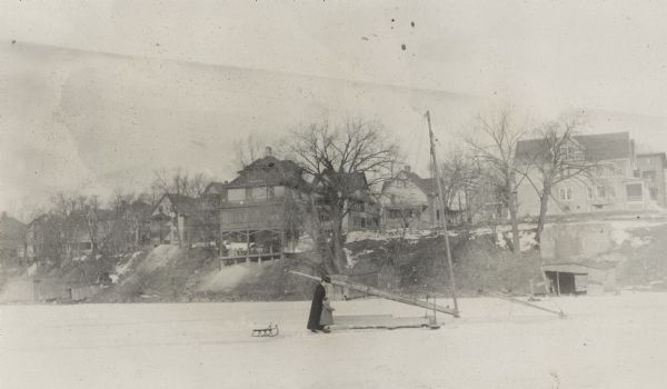 Richard "Dick" Lloyd Jones and his mother, Georgia Lloyd Jones, look at an iceboat on frozen Lake Monona.  Houses along the north shore are in the background.