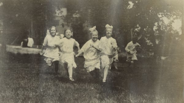 A group of four girls runs through a yard toward the camera on the east side of Madison.