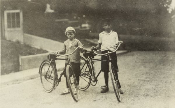 Jenkin and Dick Lloyd Jones stand with their bicycles on Walker Court.