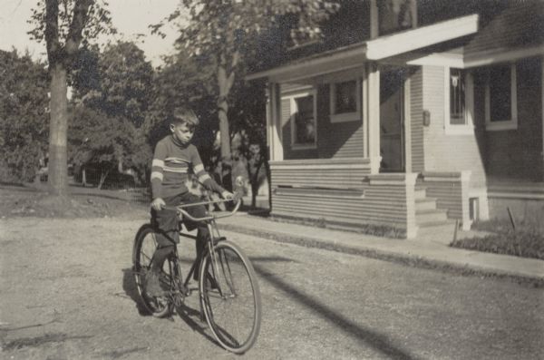 Richard "Dick" Lloyd Jones riding his bicycle in front of 1011 Walker Court (now 1011 Rutledge Court).