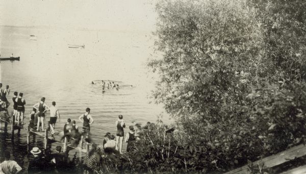 University of Wisconsin-Madison students stand on a Lake Mendota pier watching others swim.