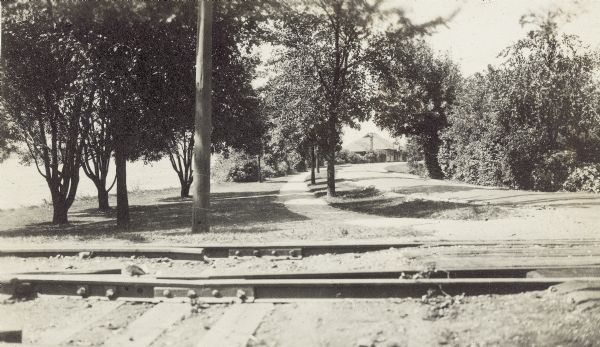 A view across railroad tracks looking west along North Shore Drive with the Brittingham Park boathouse in the background.  Monona Bay is to the left.