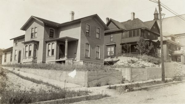 A frame house on East Wall St. was once occupied by the family of Jenkin Lloyd Jones just before they moved to Chicago.  His son, Richard Lloyd Jones was born in Janesville in 1873 and the family lived there until they moved to Chicago in 1881.  This picture was taken when Richard moved his family from Madison to Tulsa, Oklahoma, in 1919. The rectory and church (built 1902)on the far right belong to the Nativity of Mary Parish. St Mary School, 313 E. Wall St., now occupies the site.