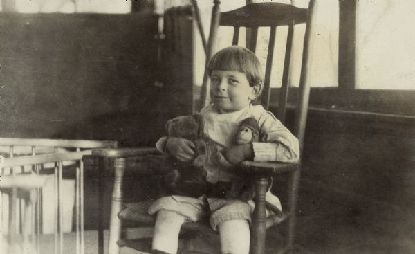Richard Lloyd Jones sits in a chair with a Teddy bear and sock monkey.