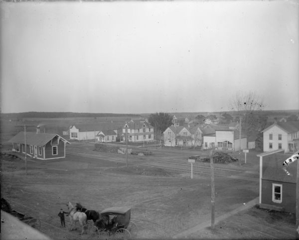 Elevated view of a residential area. Train station and horse-drawn cart in foreground.