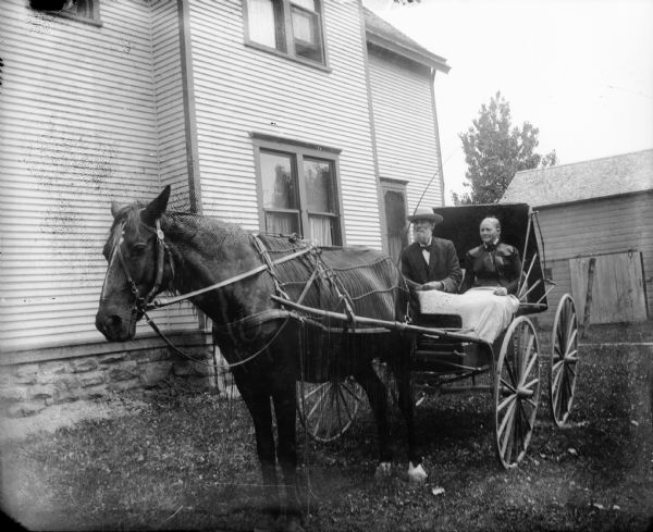 Robert Lindner and his wife sitting in a horse-drawn carriage.