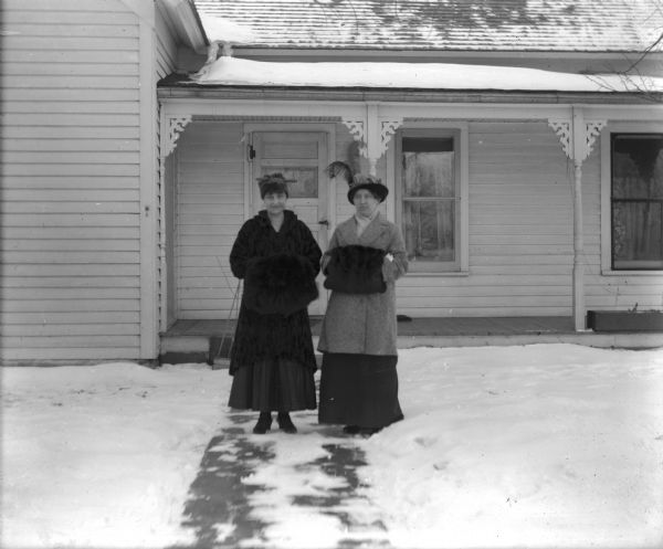 Exterior of Otto Lindner home with Mrs Thiel (wife of Lawrence University professor) and Grace Lindner. Both women are using fur hand muffs.