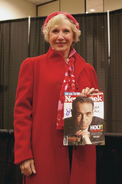 Jeannie Pope, wearing red, holding a signed copy of <i>Newsweek</i>, which reads "Holy Huckabee!" and includes an image of Republican Presidential hopeful Mike Huckabee.