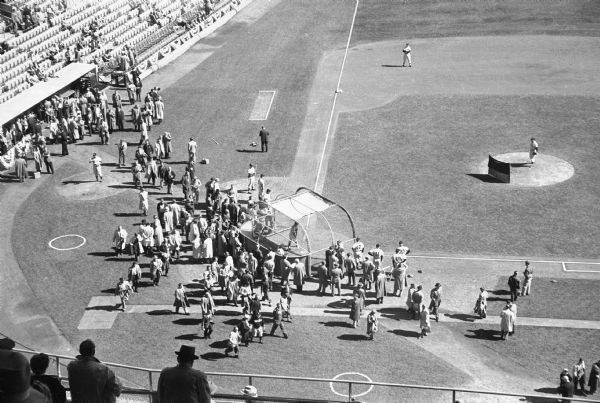Elevated view of players taking batting practice before game one of the 1958 World Series in Milwaukee County Stadium. Spectators are in the stands in the foreground.