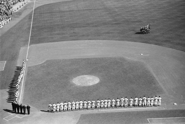 Elevated view of the Milwaukee Braves and the New York Yankees standing on the first and third baselines for the national anthem, "The Star-Spangled Banner".