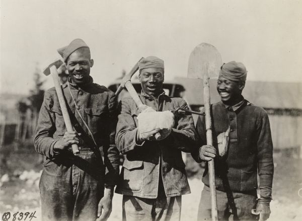 Three African American soldiers with a company of engineers somewhere in France. They are holding a shovel, pick, and sledgehammer.