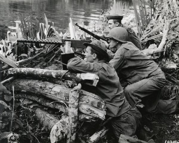 Three members of the much-decorated 32nd Division manning a machine gun emplacement in New Guinea.  They are, left to right: Lawrence Leishman of Peoria, Illinois; Corporal Rodney C. Reimar of Manitowoc; and Pvt Marin Denueli of Cumberland, Wisconsin.  The 32nd Division was originally a National Guard unit comprised of men from Wisconsin and Michigan, and during World War II it expanded to include units from many states.