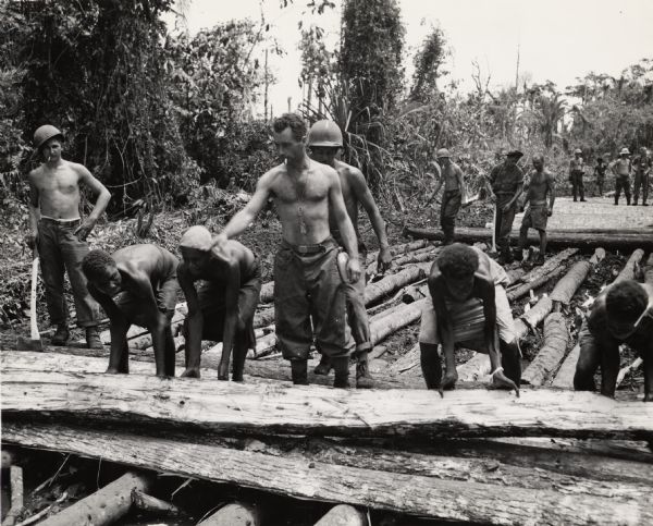 Male Papuan carriers help members of the 32nd Division construct a road through the jungle of New Guinea.