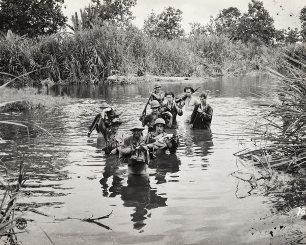 Members of the 32nd Division crossing a river somewhere in New Guinea behind Colonel H.A. Smith, commander of the division.  The much-decorated unit was originally composed of National Guard troops from Wisconsin and Michigan, but during World War II it expanded to include men from over 40 states.
