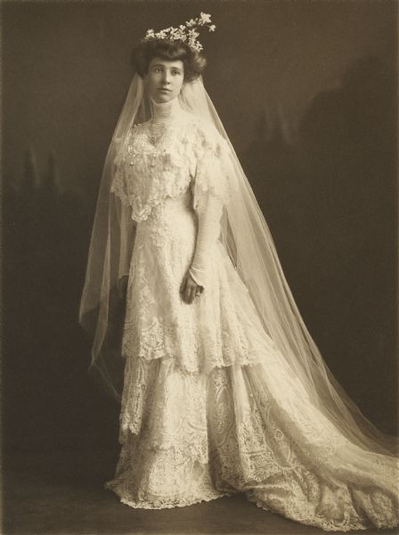 Formal portrait of Elsie Stevens, the daughter of Breese Stevens of Madison, in the princess gown of white lace over satin she wore for her wedding to Dr. Reginald Jackson, Sr.  She wore a coronet of lilies of the valley in her hair and carried a shower bouquet of the same flower.