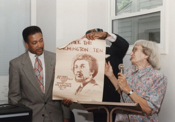 Anne Braden and Rev. Ben Chavis at an SOC (Southern Organizing Committee for Economic and Human Welfare) event.   Braden and Chavis were founding members and officers of SOC.  Between them a man is holding up a poster that marked Chavis' role as one of the Wilmington 10.