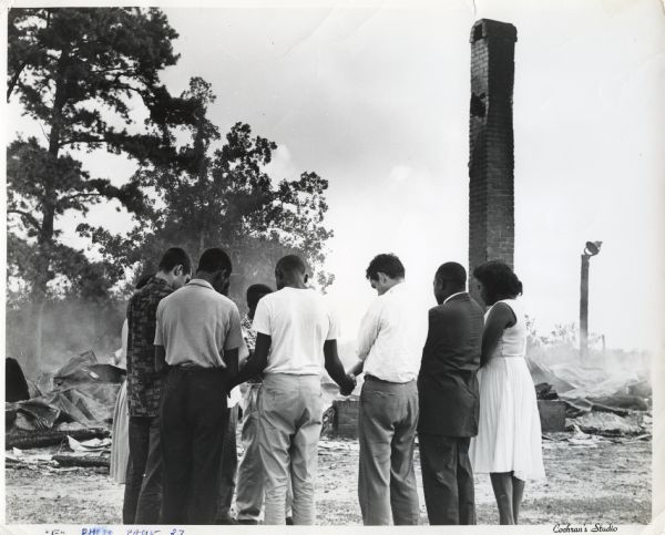 Student Non-Violence Coordinating Committee (SNCC) workers pray together near the burned remains of a church in southwestern Georgia.