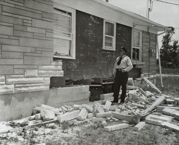 Police officer inspecting the damage to the home of Andrew Wade and his family after it was bombed.