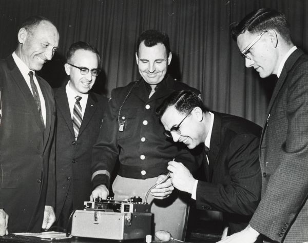Robert Warren, then the District Attorney of  Brown County, tries out a breathalizer machine.  With him are Glenn Cunningham and Ray Bayley, officers of the Alcohol Problems Council of Wisconsin; Sergeant John Berge of the Brown County Traffic Department; and Dr. Herbert Sandmire.  Warren later became the Attorney General of Wisconsin and a federal judge.