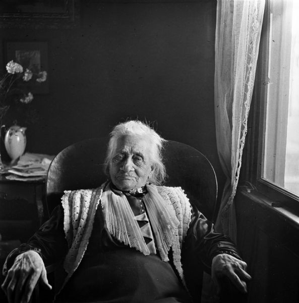 A portrait of the photographer's mother-in-law, Harriet Millard Smith. She sits in a chair next to a window.