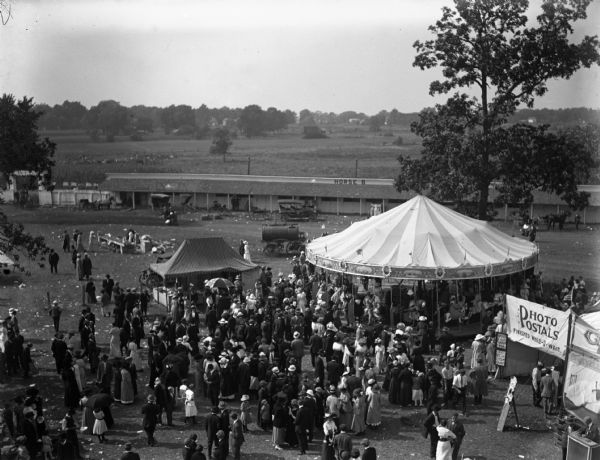 Elevated view of the Walworth County Fair. A large crowd gathers around a carousel.