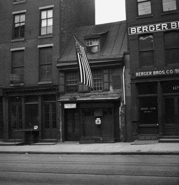 An exterior view of the Betsy Ross house. Two larger buildings flank each side of the house.