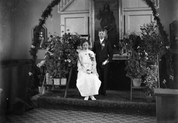 Twins Marie Johanna and Friedrich Wilhelm Ginnow pose in front of a decorated altar on their confirmation day. This was the last confirmation class at the Winneconne Lutheran Church, before the new church opened in 1914.