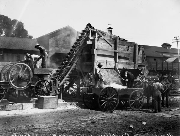 A crew of men crushing rock for Senator James H. Stout's improved highway.