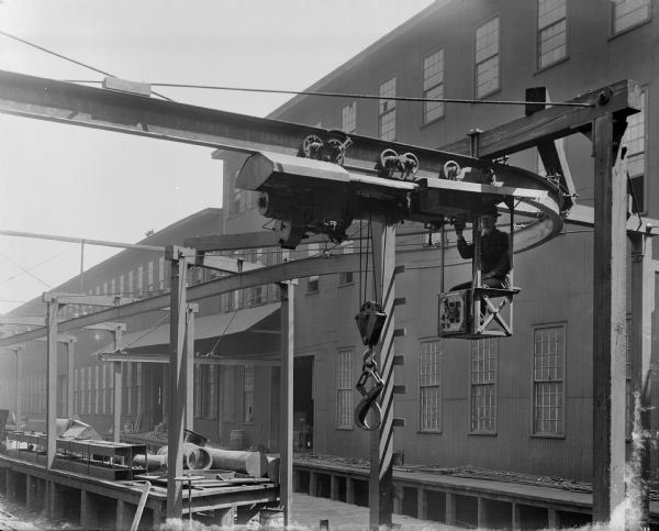 Exterior view of a Pawling & Harnischfeger monorail crane with the operator in the cab. The photographer, though not listed on the negative, is very likely Milwaukee photographer Joseph Brown.