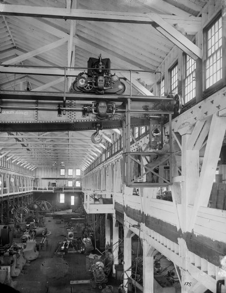 Interior view of an early Pawling & Harnischfeger standard crane in a machine shop with a type "N" bridge and a type "A" trolley. There is an operator in the cab and the bridge is stamped with "Capacity, 30,000 Lbs."