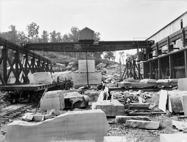 Pawling & Harnischfeger 25-ton type "C" I-beam crane holding two stone blocks at the Pfeiffer Stone Company. The crane is stamped with the text "Pawling & Harnischfeger Builders, Milwaukee, Wis., Capacity 50,000 Lbs., No. 997." The top stone being carried by the crane is carved with the words "Batesville, Marble, Crystalized Oolitic Limestone, 80 x 60 x 20, 25 Tons." and the bottom stone is carved with the words "Pfeiffer Stone Company, Batesville, Arkansas, 14'6 x 5'6 x 2'0."
