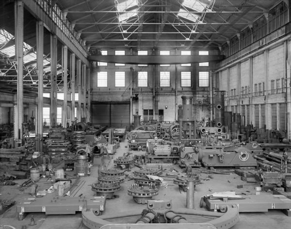A standard Pawling & Harnischfeger type "AN" hoist crane in the Nordberg Erecting shop. Many parts are sitting on the shop floor.