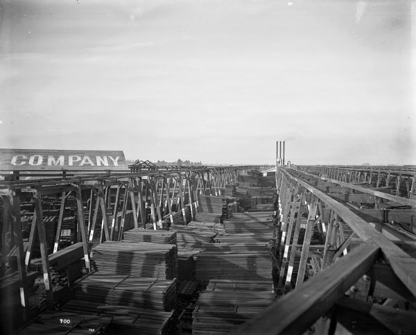 Elevated view from three monorail hoist crane tracks at the Pacific Lumber Co. lumber storage yard. Three smokestacks are in the background.