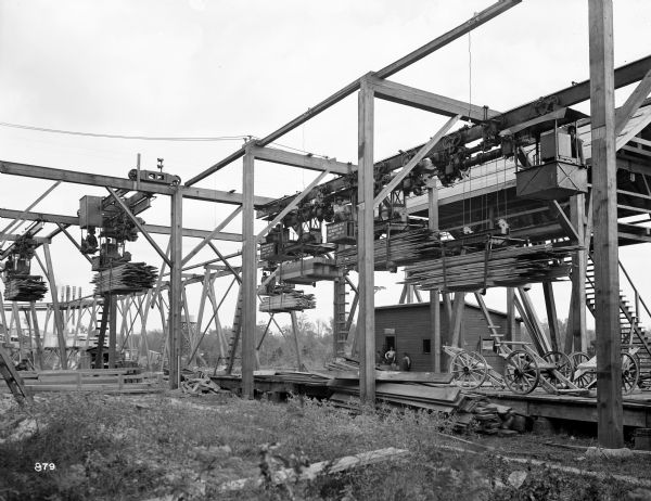 Six Pawling & Harnischfeger 3-ton monorail hoists at a lumber mill (probably Pacific Lumber Co.). There are men on the ground as well as operating the cranes.