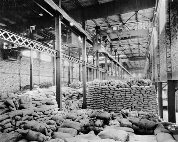 Milwaukee Electric Crane & Manufacturing Company type "AO" crane equipped with three trolleys in the American Sugar Refining Co. Two men are in the cab. The crane is stamped "Milwaukee Electric Crane & Mfg. Co., No. 819, 8 1/2 Tons."