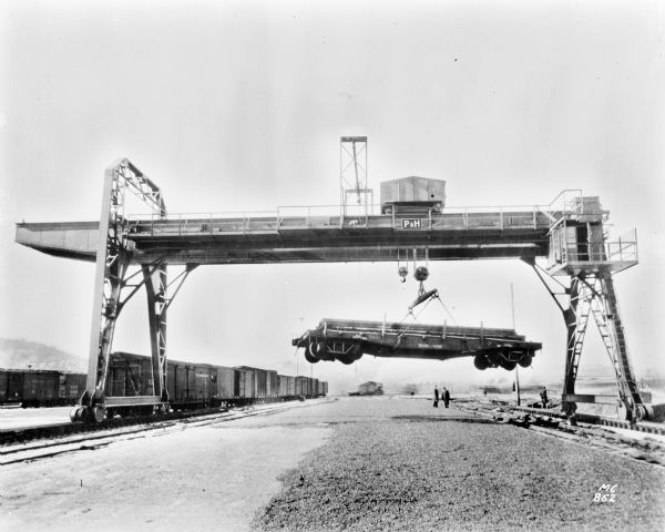 Pawling & Harnischfeger gantry crane with a specifically designed drive for handling railroad cars. Two men stand below the crane.