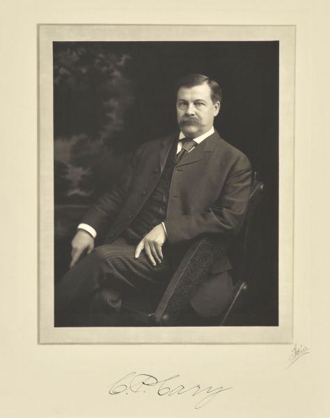 Three-quarter length seated studio portrait in front of a painted backdrop of Charles Preston Cary, Milwaukee and Madison educator.