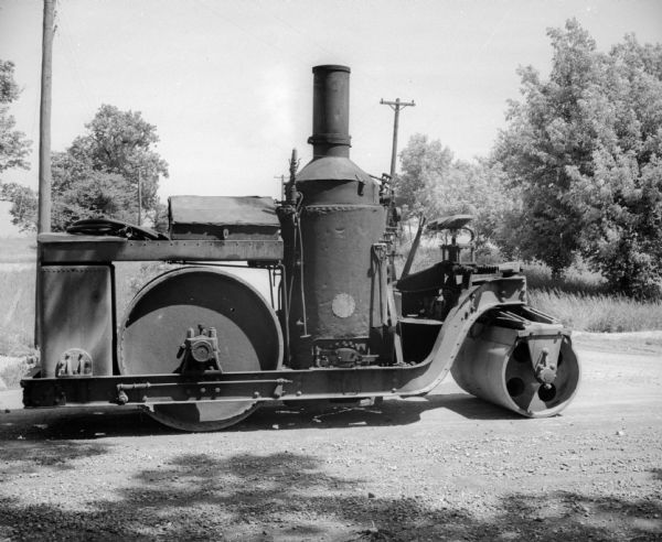 Steamroller parked on a gravel road.
