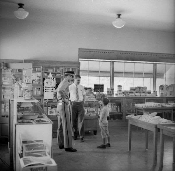 Interior of Kendall Des Jardin's drugstore on Broad Street. Two men are talking with a young boy inside the store.